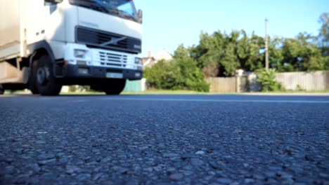 Blurred-shot-of-truck-driving-along-highway-in-country-road.-Lorry-rides-through-the-rural.-Slow-motion-Low-angle-view-Close-up