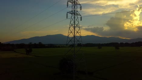 Fliegen-auf-und-rund-um-den-hohen-Spannung-Strom-Turm-mit-Sonnenuntergang