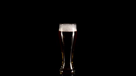 rotation-of-a-glass-of-beer-with-foam-on-a-black-background