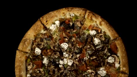 Rotating-pizza-with-smoked-sausage-and-olives-on-a-black-background.-Top-view-center-orientation