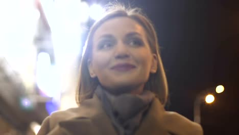 Happy-smiling-woman-in-her-30s-moving-on-lighted-city-street,-evening-promenade