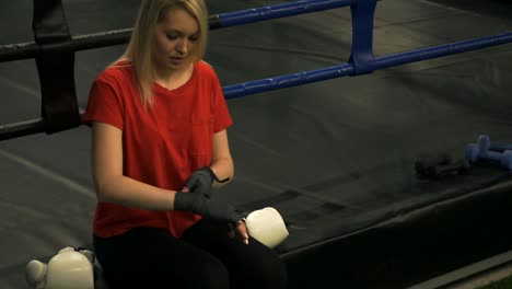 The-girl-boxer-sits-in-the-ring-and-straightens-the-bandages-on-his-hands