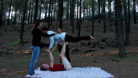 Couple-of-male-yogis-practicing-acro-yoga-with-supervision-of-female-teachers-in-forest-park