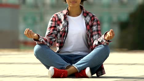 Young-afro-american-woman-meditating-yoga-in-lotus-position-on-busy-urban-street