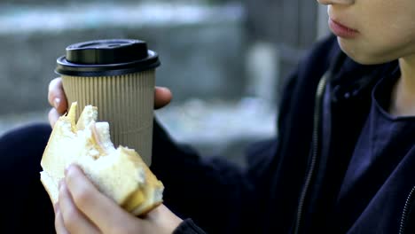 Niño-sin-hogar-comer-sandwich-y-beber-café-al-aire-libre,-la-pobreza,-closeup