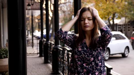 Close-up-portrait-of-a-young-businesswoman-with-headache,-a-girl-is-standing-on-the-street-tired-and-painful