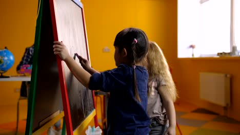 Cheerful-multi-ethnic-girls-drawing-on-chalkboard