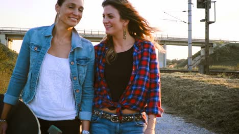 two-beautiful-and-young-women-walking-and-talking-with-skateboard