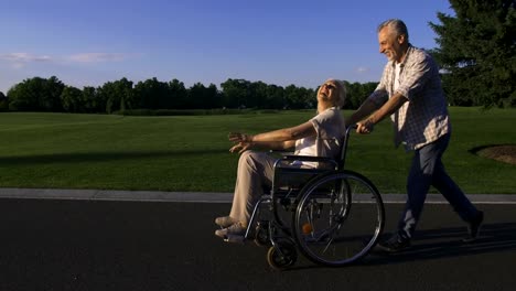 Hombre-con-esposa-en-silla-de-ruedas-disfrutando-al-aire-libre