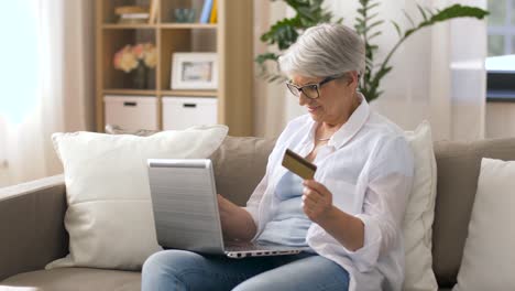 mujer-Senior-con-laptop-y-tarjeta-de-crédito-en-casa