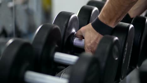 Close-up.-Hands-wraps-the-belt-on-a-dumbbell-and-take-dumbbells-4K-Slow-Mo