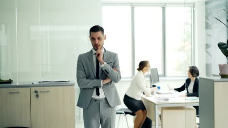 Nervous-young-man-in-smart-suit-is-waiting-for-job-interview-in-modern-office-then-walking-inside-and-starts-talking-to-interviewer.-Stress-and-youth-concept.