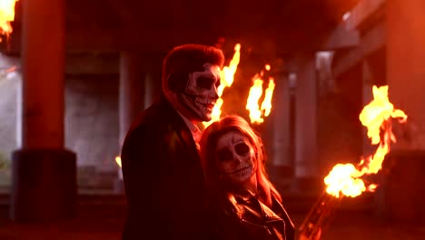 Couple-with-makeup-for-Halloween-at-a-party,-a-huge-fire-is-burning-nearby.