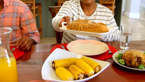 Vista-de-fuente-de-la-familia-black-tener-comida-en-la-mesa-de-comedor-en-una-casa-confortable-4k