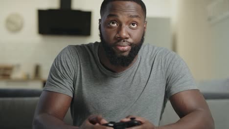 Black-man-playing-video-game-at-home.-Upset-guy-sitting-with-play-station.