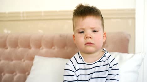 Sad-boy-sitting-on-a-couch-looks-in-camera-then-smile-in-living-room