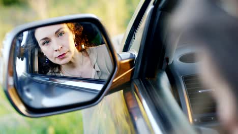 Una-mujer-llorando-está-sentada-en-el-auto.-En-el-espejo-retrovisor-corrige-el-maquillaje,-todo-en-lágrimas.-Concepto-depresión,-problemas