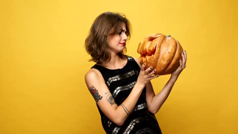 Young-displeased-lady-with-scary-make-up-holding-pumpkin-isolated-over-yellow