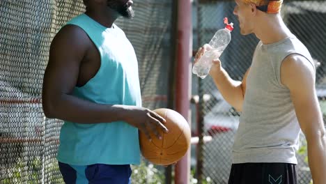 Dos-amigos-estrecharme-la-mano,-discutir-la-estrategia-de-juego-de-baloncesto-en-el-estadio