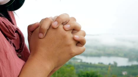 Hands-folded-in-prayer-in-a-beautiful-green-forest-with-smoke-blurred-background.