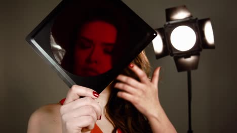 Girl-model-in-red-dress-with-red-lips-in-studio-posing-on-camera.