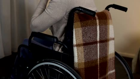 Depressed-old-lady-in-wheelchair-looking-at-window,-feels-lonely-at-nursing-home