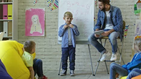 Süsser-Boy-vor-Klassenkameraden-im-Kindergarten-zu-sprechen