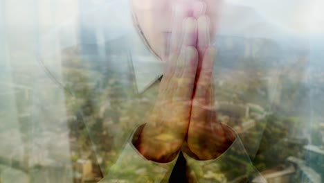 Reflection-of-a-businessman-praying-against-a-window