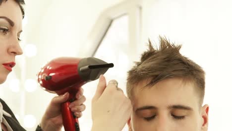 Hairstylist-drying-male-hair-after-hairdressing-in-barber-shop.-Close-up-barber-styling-hair-with-dryer-after-washing-and-cutting.-Finish-hairdressing-in-beauty-salon