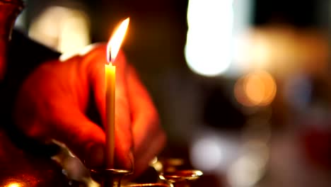 Primer-plano-de-la-mano-del-hombre-coloca-una-vela-en-un-candelabro-en-la-iglesia-ortodoxa-cristiana