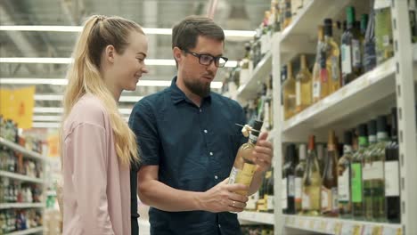 Joven-pareja-es-hablar-de-vino-en-un-departamento-de-supermercado