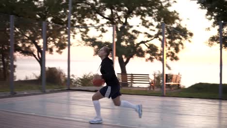 Handhelded-footage-of-a-young-girl-basketball-player-training-and-exercising-outdoors-on-the-local-court.-Dribbling-with-the-ball,-bouncing-and-make-a-shot