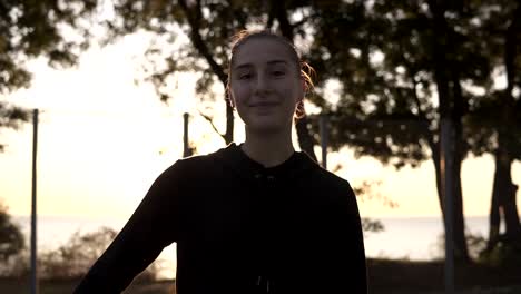 Footage-from-down-and-up-below-a-full-length-of-a-young-female-basketball-player-in-hoodie-and-shorts-standing-on-a-local-basketball-court-with-ball-in-her-hand.-Morning-time