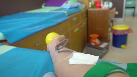 Donación-de-sangre.-Mano-masculina-de-bola-de-goma-de-sangre-donante-y-exprimir-para-golpes-de-sangre-en-el-hospital.