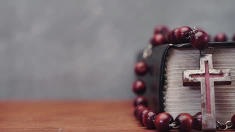 Bible-and-the-crucifix-beads-on-a-red-wooden-table.-Beautiful-background.-Religion-concept-close-up