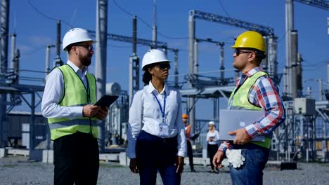 Tres-trabajadores-de-la-electricidad-revisar-documentos-en-forma-de-tabletas