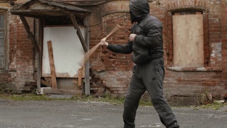 Aggressive-Bandit-in-schwarzer-Maske-und-Haube-training-mit-Baseballschläger-zu-kämpfen