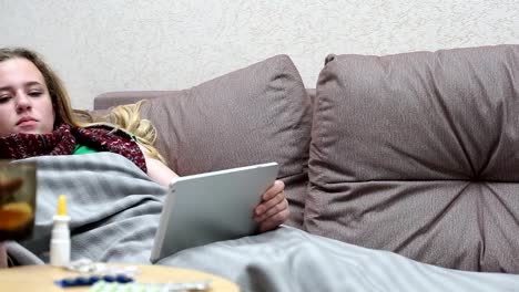 Teengirl-Medizin-Tee-warm-trinken.-Mit-einem-Tablet-liegen-auf-der-couch