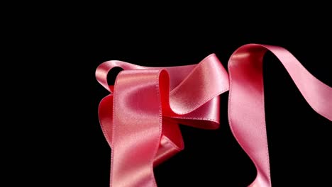 Satin-ribbon-on-a-black-background.-Slow-motion.