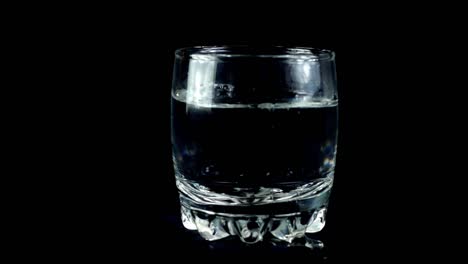 Water-in-a-glass-on-a-black-background.-Slow-motion.