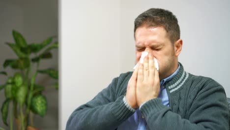 Handsome-unshaved-man-blowing-nose-to-napkin.