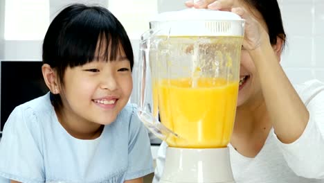 Madre-y-usando-poco-jugo-de-licuadora-en-la-cocina.-Ellos-haciendo-jugo-de-naranja-para-beber.-Personas-con-estilo-de-vida-y-el-concepto-saludable.