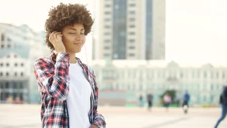 Pretty-young-female-in-headphones-listening-favorite-song-and-singing-outdoors