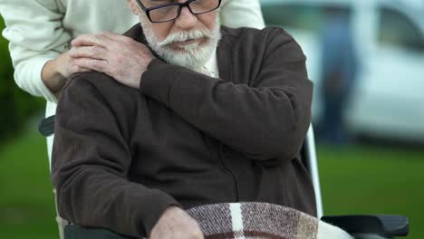 Female-pushing-old-man-in-wheelchair,-care-and-compassion-in-nursing,-closeup