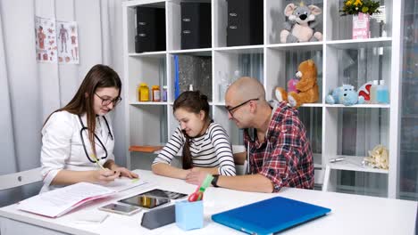 4K-amable-doctor-hablando-con-el-paciente-niño-y-padre-en-la-oficina.