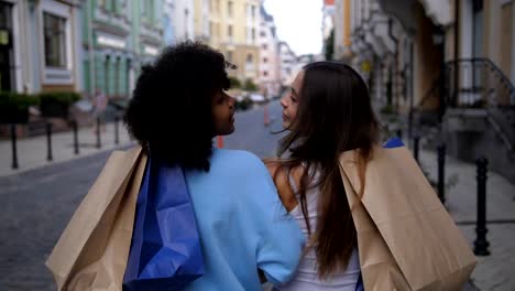 Raza-mezclada-y-caucásicas-chicas-con-bolsas-sonriendo