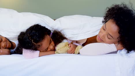 Front-view-of-black-family-sleeping-under-blanket-in-bedroom-at-home-4k