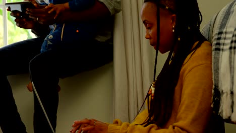 Side-view-of-young-black-mother-using-laptop-and-sitting-on-floor-of-comfortable-home-4k