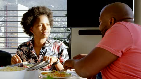 Father-teaching-his-son-eating-with-fork-and-knife-at-dining-table-4k