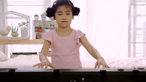 4K:-Asiatische-Skid-Mädchen-trainiert,-um-ein-E-Piano-zu-spielen.-Ist-eine-Aktivität,-die-emotionale-Fähigkeiten-trainiert-Und-der-Körper-gut-studieren-zu-Hause-oder-Musikschule-Musik.-gute-psychische-Gesundheit-und-gute-Laune.